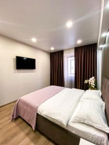 a bedroom with a large bed and a flat screen tv at Central City Apartments in Ustʼ-Kamenogorsk