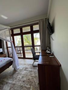 a bedroom with a desk and a bed and a window at Zanzibar Star Resort in Nungwi