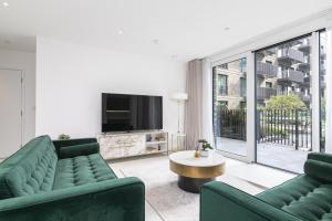 倫敦的住宿－Rooms in Shared Luxury Flat，客厅配有两张绿色沙发和一台电视机