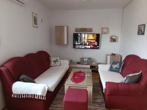 un soggiorno con 2 divani rossi e una TV di Margareta's Apartment a Kaštela (Castelli)