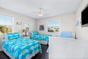 a bedroom with two beds and a flat screen tv at Beachy Keen Cottage in Clearwater Beach