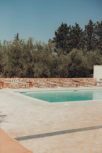 een zwembad met tafels, stoelen en bomen bij Il Villaggetto in Neviano