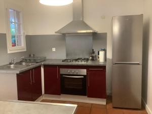 una cucina con armadi rossi e frigorifero in acciaio inossidabile di VILLA ALIZEE APPARTEMENT 2 a Sainte-Rose
