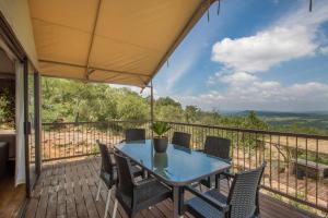 a patio with a table and chairs on a balcony at Idwala Le Ingwe Lodge in Hekpoort