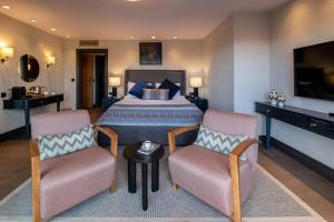 a bedroom with a bed and two chairs and a television at Root Karaköy in Istanbul
