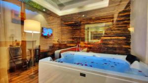 Hotel Royale Retreat - Luxury Hotel In Shimla في شيملا: حوض جاكوزي في غرفة مع جدار حجري