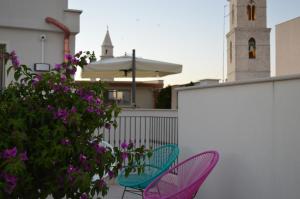 - 2 chaises et un parasol sur un balcon orné de fleurs violettes dans l'établissement Borgomurgia, à Andria