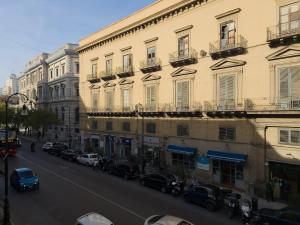 una calle de la ciudad con coches estacionados frente a los edificios en B&B Liberty, en Palermo