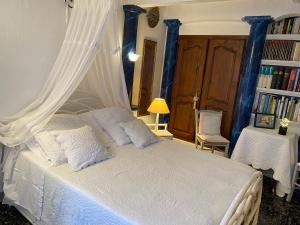 a bedroom with a white bed with blue curtains at La Florentine in Bandol
