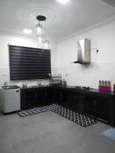 a kitchen with a black counter top and a tv at Inap Singgah Homestay in Kota Bharu