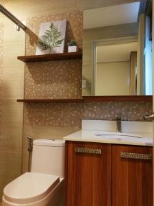 a bathroom with a toilet and a sink and a mirror at Adria Residences - Ruby Garden - 2 Bedroom for 4 person in Manila