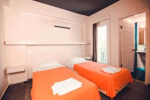 two beds in a room with orange sheets at Muskebi Apart Otel in Ortakent