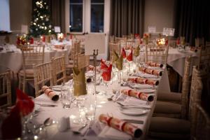 une longue table dans une pièce avec un sapin de Noël dans l'établissement The Dower House Hotel, à Woodhall Spa