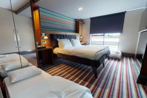 a hotel room with two beds and a window at Village Hotel Leeds South in Leeds