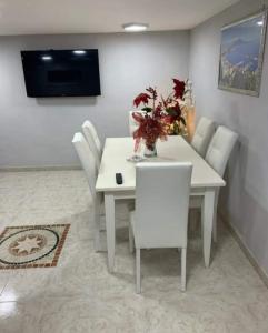 a white dining room table with white chairs and a television at Casa Antonella in Naples