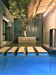 einen Pool mit vier Bänken in einem Zimmer mit einem Baum in der Unterkunft Villa by the Win Pattaya in Jomtien Beach