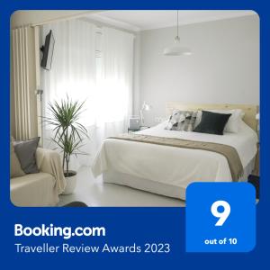 a white bedroom with a bed and a chair at At home, in the Heart of Sitges in Sitges
