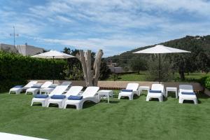 een groep witte stoelen en parasols op het gras bij Villa Simona Ibiza in Ibiza-stad