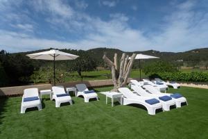 Villa Simona Ibiza في مدينة إيبيزا: مجموعة من الكراسي البيضاء والمظلات على العشب