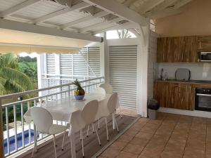 a dining room with a table and chairs on a balcony at VILLA ALIZEE APPARTEMENT N°6 in Sainte-Rose