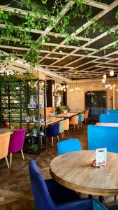 a restaurant with tables and chairs and plants at Cruce de Gustos in Ivano-Frankivsʼk