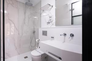 a white bathroom with a shower and a sink at Hotel La Milagrosa in Alicante