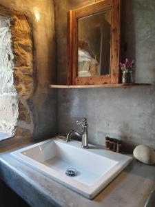 ein weißes Waschbecken im Bad mit Spiegel in der Unterkunft Chios Houses, beautiful restored traditional stone houses with an astonishing seaview in Volissos