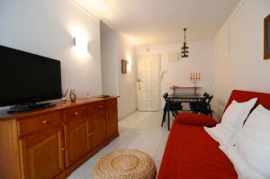 een woonkamer met een tv en een rode bank bij Enric Serra 54 in L'Escala
