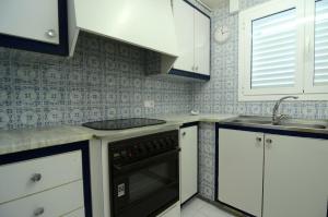 una cocina con armarios blancos y horno negro en Enric Serra 54, en L'Escala