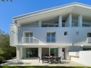 ein weißes Haus mit einem Tisch und Stühlen in der Unterkunft Esclusiva Villa Frontemare in Tana della Volpe 2 in Lignano Sabbiadoro