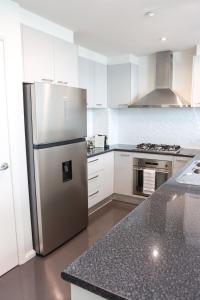 a stainless steel refrigerator in a kitchen with white cabinets at Bendigo Townhouse - Walk to the CBD in Bendigo