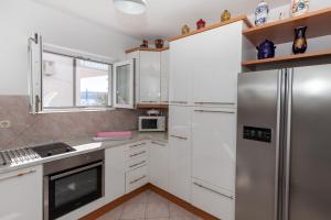 a kitchen with white cabinets and a stainless steel refrigerator at Strandhaus Vesna EG 3 in Klek