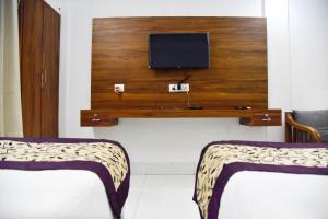 a room with two beds and a tv on a wall at Hotel Su Pinsa in Itānagar
