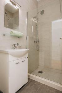 a white bathroom with a sink and a shower at Sunny Side apartment in Bečići