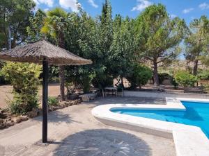 a straw umbrella next to a swimming pool at El Rulón, gran villa rural con piscina privada in Alicante