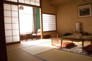 a living room with a table and a chair at NOZARU ONSEN HOSTEL in Yamanouchi