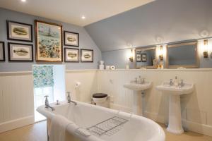 a bathroom with two sinks and a tub and two mirrors at The Granary Lodge Bed & Breakfast in Thurso