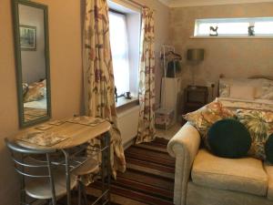 a bedroom with a bed and a table and a mirror at The Annex Rocket cottage in Sidestrand