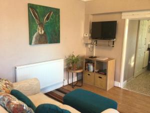 a living room with a couch and a painting of a rabbit at The Annex Rocket cottage in Sidestrand