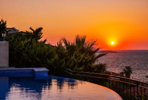 una piscina con tramonto sullo sfondo di Villa Mavi Manzara a Kaş