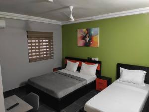 2 camas en una habitación con paredes verdes en Room in Guest room - Royal Blue Guest House Bar Deluxe Twin Bed, en Lomé