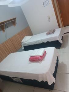 two beds in a room with a red item on them at Hotel Jerusalém 2 in Goiânia