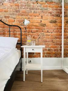 a bed and a white table next to a brick wall at Chabrowy - Apartamenty Smart Projekt in Tarnów