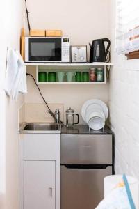 a small kitchen with a sink and a microwave at Maldon Cosy Garden Cottage - Charming One Room Studio in Maldon