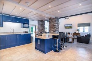 a kitchen with blue cabinets and a living room at Ty'r Efail in Llanrwst
