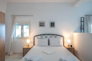 een slaapkamer met een wit bed, 2 tafels en 2 ramen bij Vrisidia Cottage - Nature, Seaview & Relax in Plakias