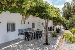 a patio with a table and chairs under a tree at Vrisidia Cottage - Nature, Seaview & Relax in Plakias