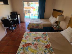 a hotel room with two beds and a table and a desk at Parador Palmas de Lucia in Yabucoa