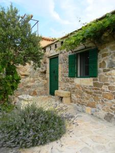 - un bâtiment en pierre avec une porte verte et une fenêtre dans l'établissement Lavender Cottage, à Trpanj