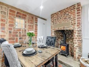 a living room with a wooden table and a brick fireplace at Stoney Nook Cottage in Guisborough